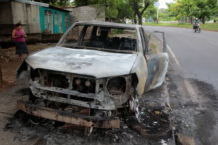 A woman stands next to a burned car after a protest against Nicaraguan President Daniel Ortega's government in Managua, Nicaragua May 31, 2018.REUTERS/Oswaldo Rivas