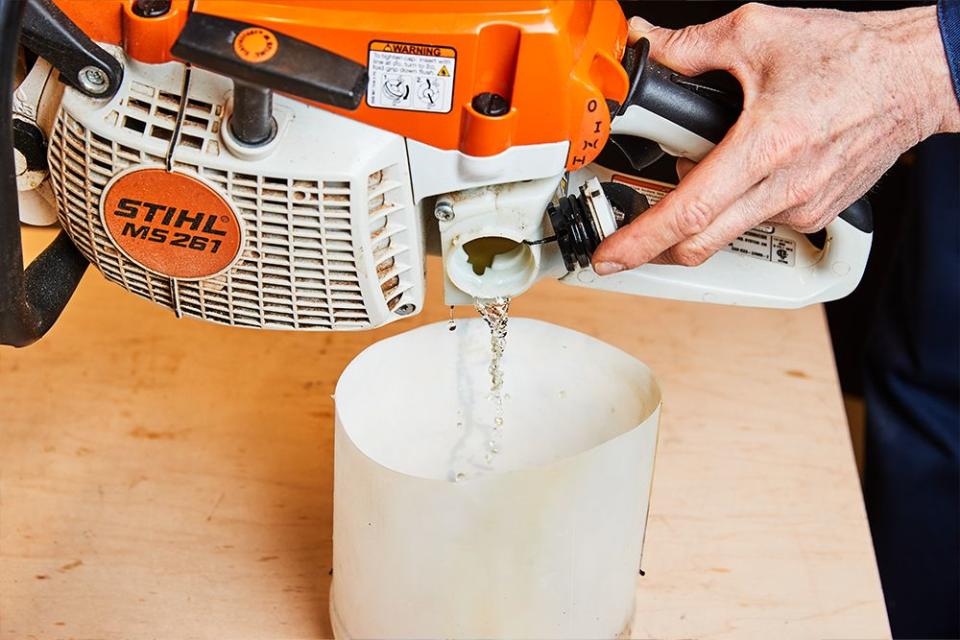 a person draining stale two stroke fuel mixture from a chainsaw