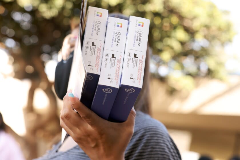 MONTEBELLO, CA - MARCH 03: Glenda Cutzan carries COVID-19 test kits distributed by workers with AltaMed Health Services outside Greenwood Elementary School on Thursday, March 3, 2022 in Montebello, CA. (Dania Maxwell / Los Angeles Times)