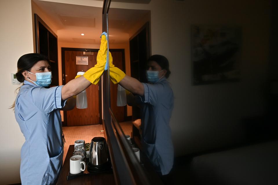 A member of the cleaning staff cleans surfaces as she prepares a room for a guest at the St Giles Hotel, near Heathrow Airport in west London, on February 10, 2021. - The Hotel has offered to become one of England's designated Covid-19 quarantine hotels. Health Secretary Matt Hancock told parliament that British or Irish residents arriving from 33 countries deemed high risk of new variants will have to stay in one of 16 designated hotels in England. Travellers will have to stay in their rooms, have meals delivered to them and pay out their own pocket. (Photo by Ben STANSALL / AFP) (Photo by BEN STANSALL/AFP via Getty Images)