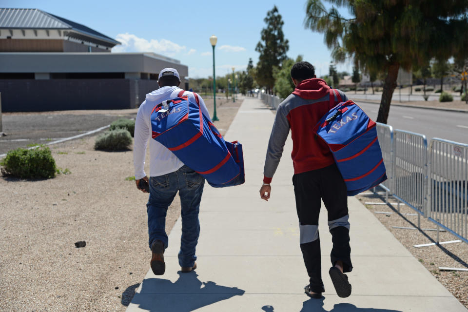 Mar 15, 2020; Surprise, Arizona, USA; Texas Rangers prospects Tyreque Reed (white shirt) and Bubba Thompson (red/gray shirt) leave Surprise Stadium following the cancellation of spring training games due to concerns over the COVID-19 coronavirus. Mandatory Credit: Joe Camporeale-USA TODAY Sports