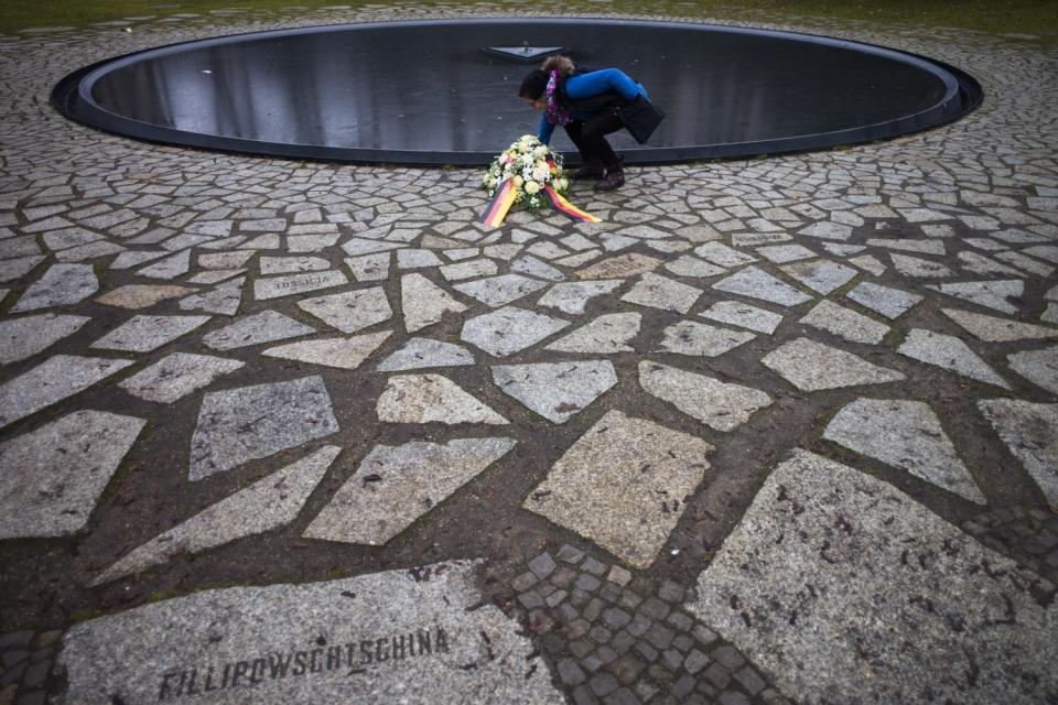 A woman lays flowers at the Memorial to the Sinti and Roma Victims of the Holocaust