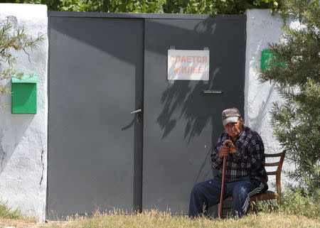 A man sits at the entrance of his house in the port city of Yevpatoriya, Crimea, June 27, 2014. The sigh reads, "Accommodation to let". Picture taken June 27, 2014. REUTERS/Pavel Rebrov
