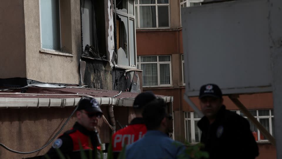 Police officers stand next to the burned building in Istanbul. - Murad Sezer/Reuters