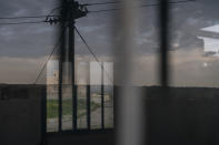 In this April 10, 2019 photo, houses are reflected in the window of an Iraqi army base in Badoush, Iraq. Badoush, on the Tigris River just outside the city of Mosul, is a key battleground because it was once one of the most diehard IS strongholds. (AP Photo/Felipe Dana)