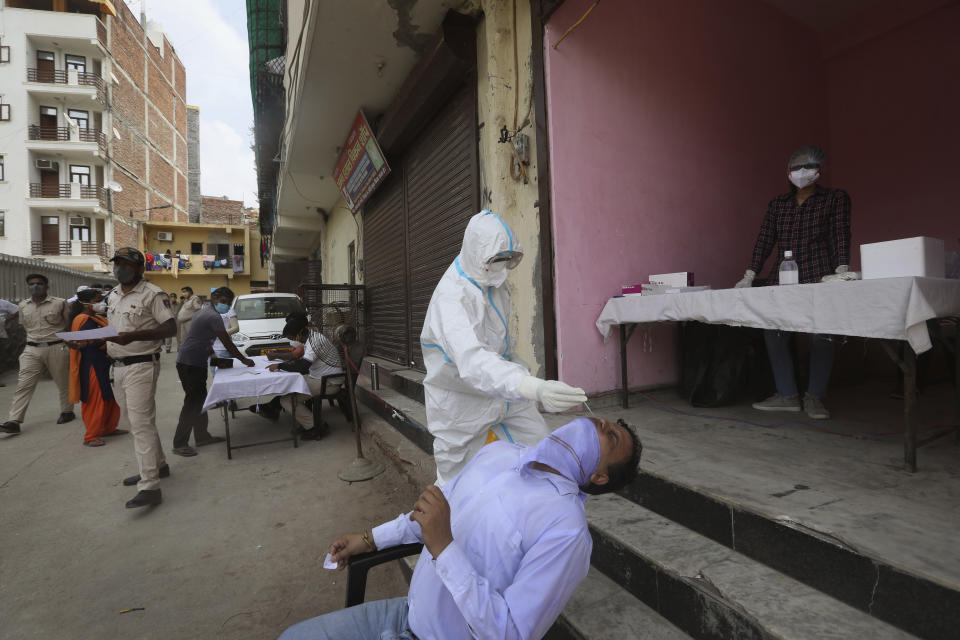 A health worker takes a nasal swab sample for COVID- 19 testing through rapid antigen methodology, in New Delhi, India , Friday, Aug. 7, 2020. As India hit another grim milestone in the coronavirus pandemic on Friday, crossing 2 million cases and more than 41,000 deaths, community health volunteers went on strike complaining they were ill-equipped to respond to the wave of infection in rural areas. (AP Photo/Manish Swarup)