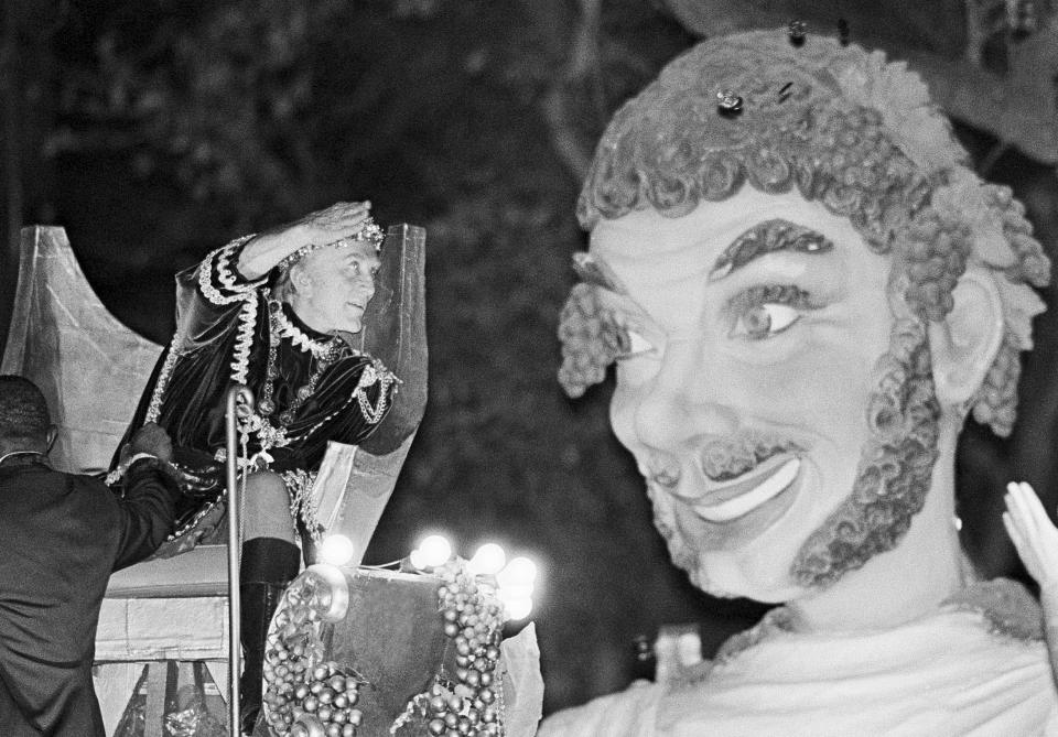 Bacchus the XVII, also known as Kirk Douglas, tosses doubloons from a carnival float on Mar. 4, 1984 in New Orleans. The popular Bacchus parade was one of several Sunday. The celebrations end with Rex and other Mardi Gras extravaganzas on Tuesday. (AP Photo/Bill Haber, file)