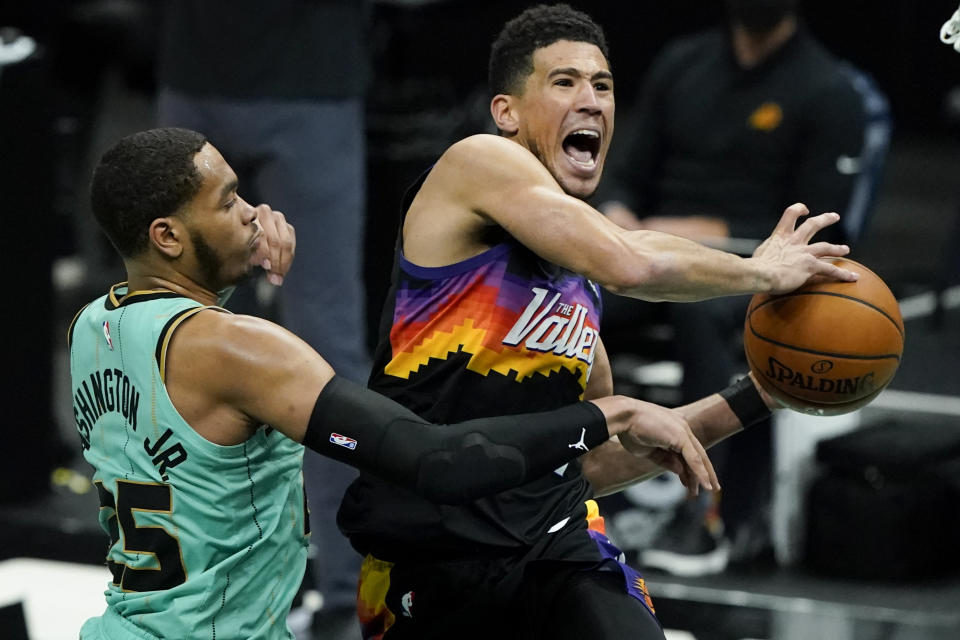 Phoenix Suns guard Devin Booker, right, is fouled by Charlotte Hornets forward P.J. Washington during the second half of an NBA basketball game on Sunday, March 28, 2021, in Charlotte, N.C. (AP Photo/Chris Carlson)