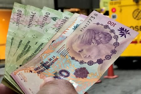 FILE PHOTO: A man shows Argentine pesos outside a bank in Buenos Aires' financial district