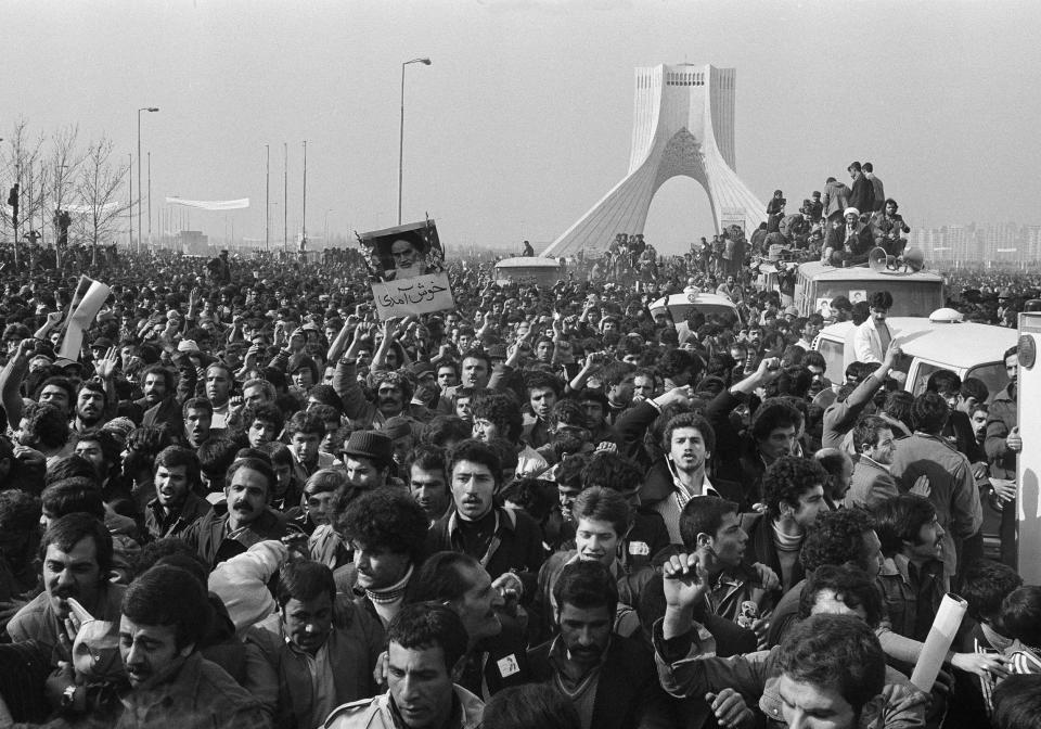 FILE - In this Feb. 1, 1979 file photo, the motorcade of Ayatollah Ruhollah Khomeini is lost among the throngs of supporters at the Shayad, a landmark memorial to the shah, near the airport in Tehran, Iran. Friday, Feb. 1, 2019 marks the 40th anniversary of Khomeini's arrival in Iran, setting the stage for the country's 1979 Islamic Revolution that changed the country’s history for decades to come. (AP Photo/FY, File)