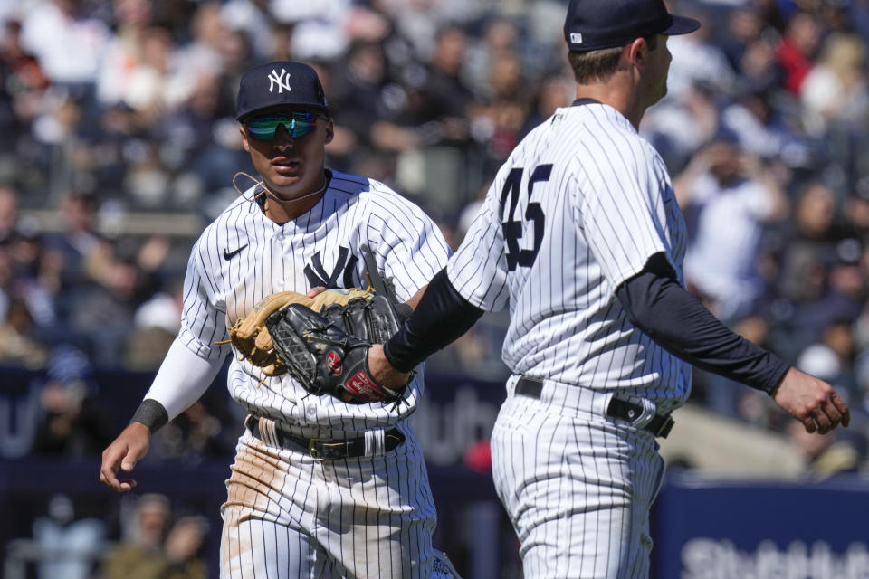 New York Yankees' Anthony Volpe, left, reacts with starting pitcher Gerrit Cole after throwing out a runner at first base during the fourth inning of a baseball game against the San Francisco Giants at Yankee Stadium Thursday, March 30, 2023, in New York. (AP Photo/Seth Wenig)