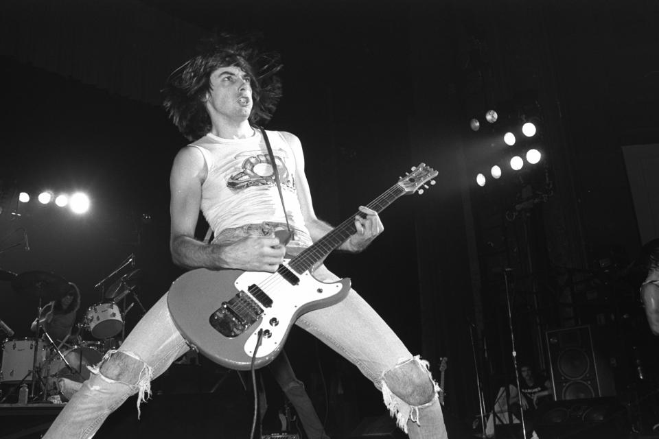 Johnny Ramone playing guitar at the forefront with Tommy Ramone on drums at the back