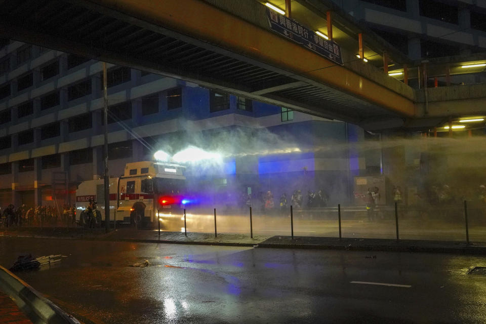 Police fire water cannon toward demonstrators during a protest as they roll out the water cannon truck for the firs time in Hong Kong, Sunday, Aug. 25, 2019. One year ago, a sea of humanity - a million people by some estimates - marched through central Hong Kong on a steamy afternoon. It was the start of what would grow into the longest-lasting and most violent anti-government movement the city has seen since its return to China in 1997.(AP Photo/Vincent Yu, File)