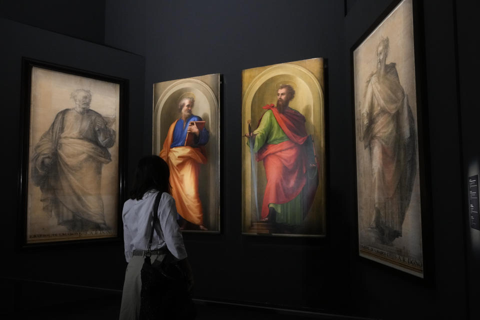 A woman admires, from left, a black and white preparatory cartoon for the St. Peter painting, by Fra Bartolomeo, 1513, the oil on wood painting of St. Peter, by Raffaello, 1517-1518, the oil on wood painting of St. Paul, by Fra Bartolomeo, 1513, and it's black and white preparatory cartoon, by Fra Bartolomeo, 1513-1514, during a press preview of the "St.Peter and St.Paul by Fra Bartolomeo and Raffaello" exhibition, at the Vatican Museums, at the Vatican, Friday, Sept. 24, 2021. The two restored paintings, started by Fra Bartolomeo and finished by Raffaello after his death, that have been kept in the Papal Apartments, unseen by the public for decades, and the two cartoons by Far Bartolomeo, coming from Forence's Uffizi Museum, will be on display from Sept. 25, 2021 to Jan. 9, 2022. (AP Photo/Andrew Medichini)