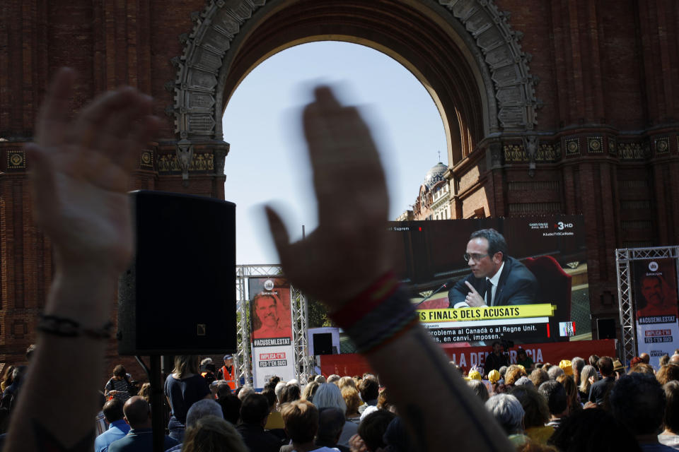 People look at a big TV screen showing the trial at Spain's Supreme Court happening Madrid on Wednesday, June 12, 2019, as they gather in downtown Barcelona, Spain. A dozen politicians and activists on trial for their failed bid in 2017 to carve out an independent Catalan republic in northeastern Spain will deliver their final statements Wednesday as four months of hearings draw to an end. (AP Photo/Emilio Morenatti)