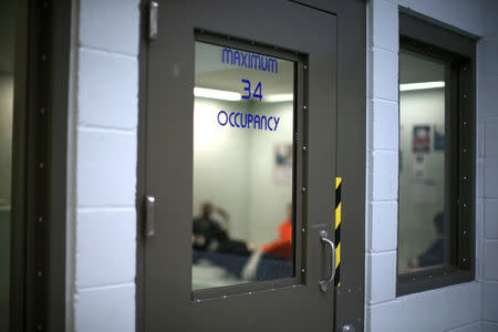 FILE PHOTO: Immigrants sit in a cell for incoming ICE detainees at the Adelanto immigration detention center, which is run by the Geo Group Inc (GEO.N), in Adelanto, California, U.S., April 13, 2017. REUTERS/Lucy Nicholson/File Photo