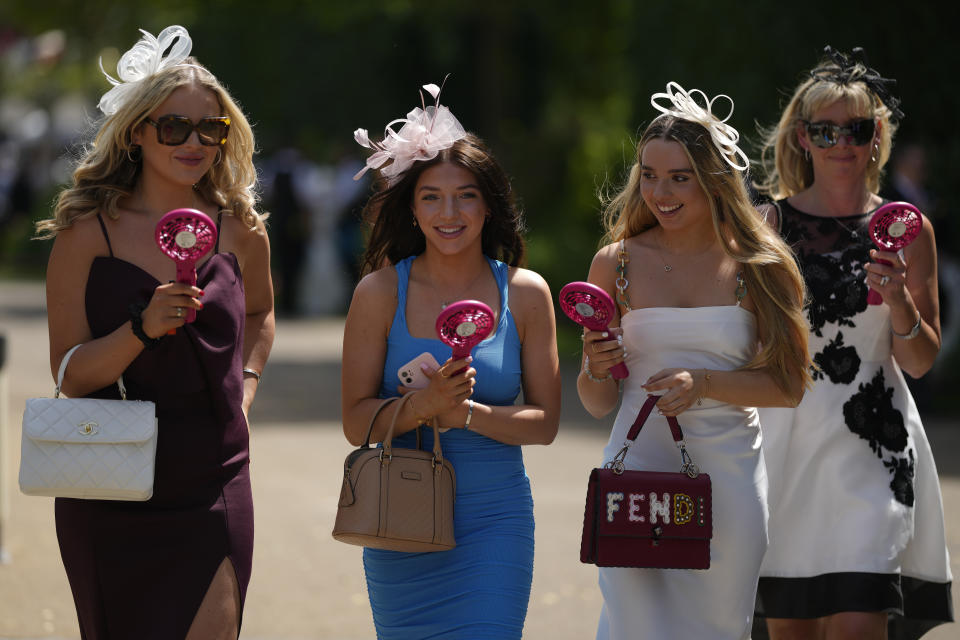 Racegoers carrying portable fans to keep cool arrive for the fourth day of the Royal Ascot horserace meeting, at Ascot Racecourse, in Ascot, England, Friday, June 17, 2022. This year's Ascot coincided with a mini heatwave that bathed Britain and parts of Europe in blistering sunshine, with temperatures hitting almost 33 degrees Celsius on Friday, the hottest day of the year so far in the U.K. (AP Photo/Alastair Grant)