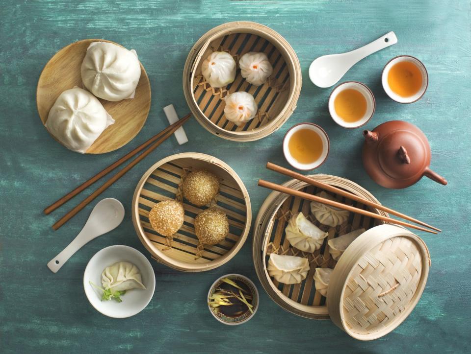 overhead view chinese food assorted dim sum food in bamboo steamer tray on rustic green table top chinese style breakfast with tea