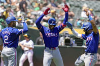 Texas Rangers' Leody Taveras, center, celebrates with Marcus Semien, left, and Ezequiel Duran after hitting a two-run home run against the Oakland Athletics during the fourth inning in the first baseball game of a doubleheader Wednesday, May 8, 2024, in Oakland, Calif. (AP Photo/Godofredo A. Vásquez)