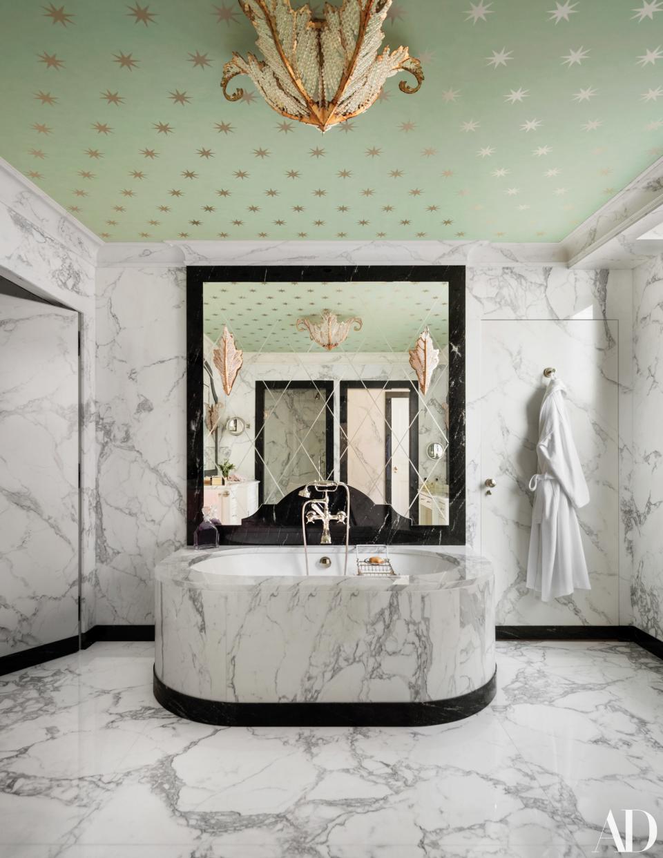 The ceiling in the marble-clad master bath is covered in an Osborne & Little wallpaper.