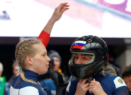 FILE PHOTO: Russia's pilot Olga Stulneva (L) looks at teammate Liudmila Udobkina as she takes off her helmet after completing a run in the women's bobsleigh event at the 2014 Sochi Winter Olympics, at the Sanki Sliding Center in Rosa Khutor February 19, 2014. REUTERS/Arnd Wiegmann/File Photo