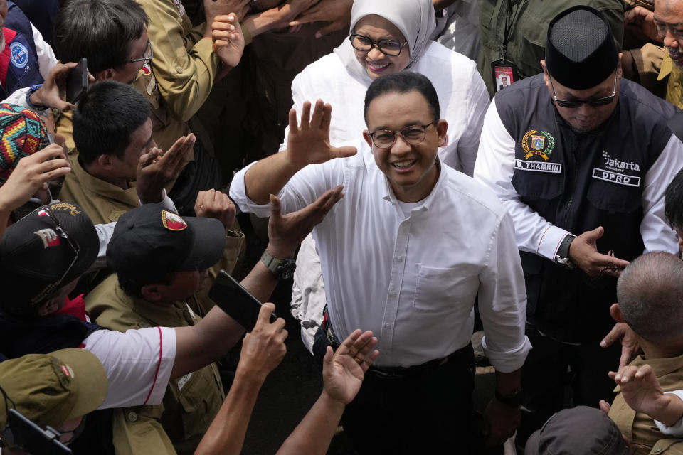 Presidential candidate Anies Baswedan, center, waves at the media upon arrival at a stadium for a campaign rally in Jakarta, Indonesia, Tuesday, Nov. 28, 2023. Candidates officially began their campaign for next year's election which will determine who will succeed President Joko Widodo who is now serving his second and final term. (AP Photo/Achmad Ibrahim)