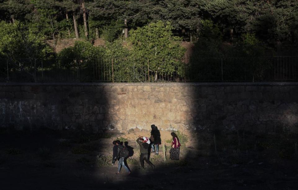 A group of people walk at sunset next to a railway in Van city after crossing the Iran-Turkey border, on 8 June 2021.