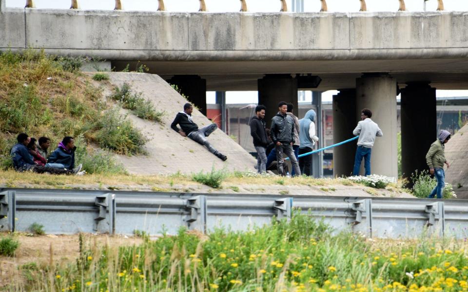 Migrants wait on the roadside along the ring road leading to the port of Calais - Credit: DENIS CHARLET/AFP