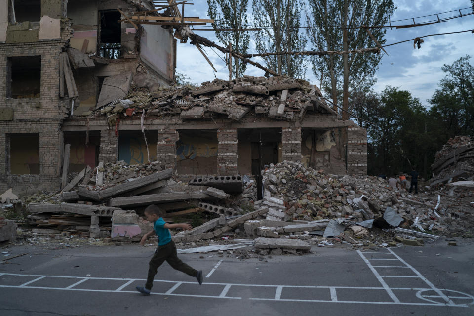 Oleksii Makarov, 6, runs past the building where his classroom was located as he plays in the courtyard of the destroyed School Number 23 after a Russian attack that occurred in the second half of July, in Kramatorsk, Ukraine, Saturday, Aug. 27, 2022. (AP Photo/Leo Correa)