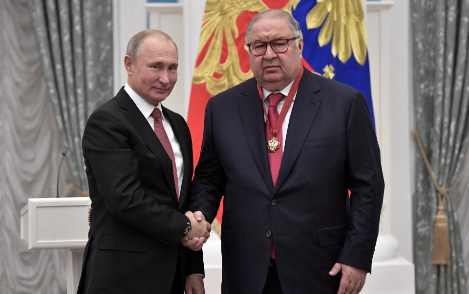 Vladimir Putin shakes hands with Russian businessman and founder of USM Holdings Alisher Usmanov