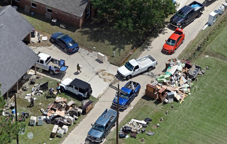 Residents gather house debris for the trash near Highway 16 in Denham Springs, La., as people begin the recovery process from the severe weather flooding in Livingston Parish, east of Baton Rouge, La., on, Aug. 16, 2016.