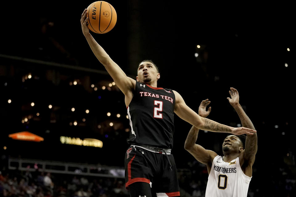 Texas Tech guard Pop Isaacs (2) gets past West Virginia guard Kedrian Johnson (0) to put up a shot during the first half of an NCAA college basketball game in the first round of the Big 12 Conference tournament Wednesday, March 8, 2023, in Kansas City, Mo. (AP Photo/Charlie Riedel)