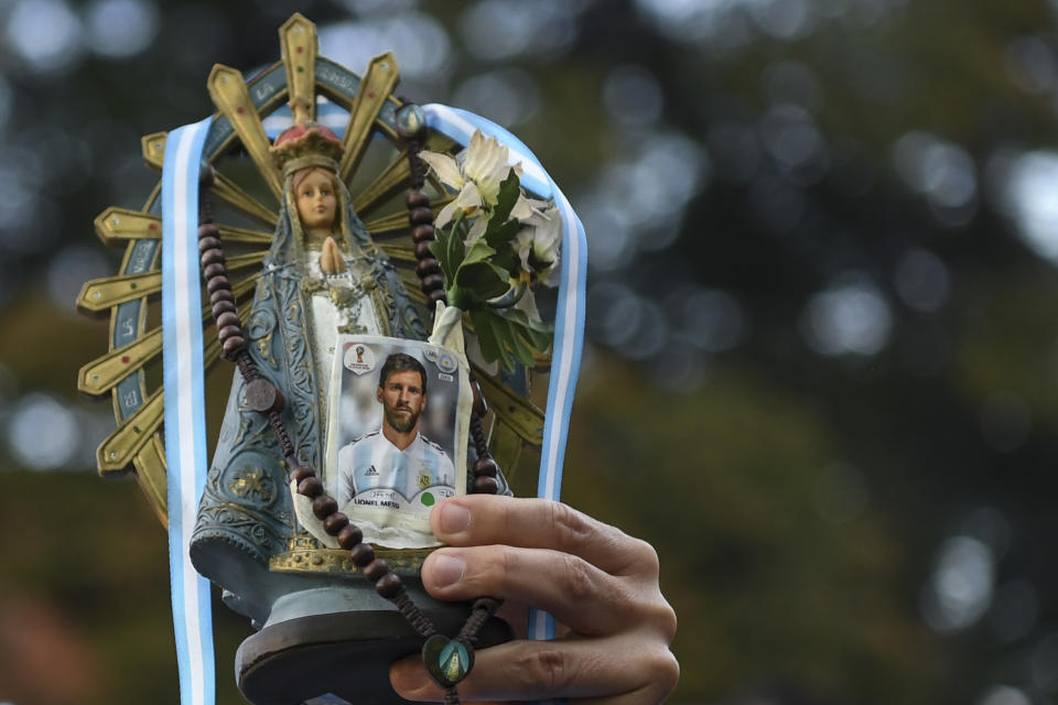 Un hincha de Argentina sostiene una imagen de la Virgen y una estampita del álbum de Panini del delantero argentino Lionel Messi. (Foto: por Eitan ABRAMOVICH/AFP a través de Getty Images)