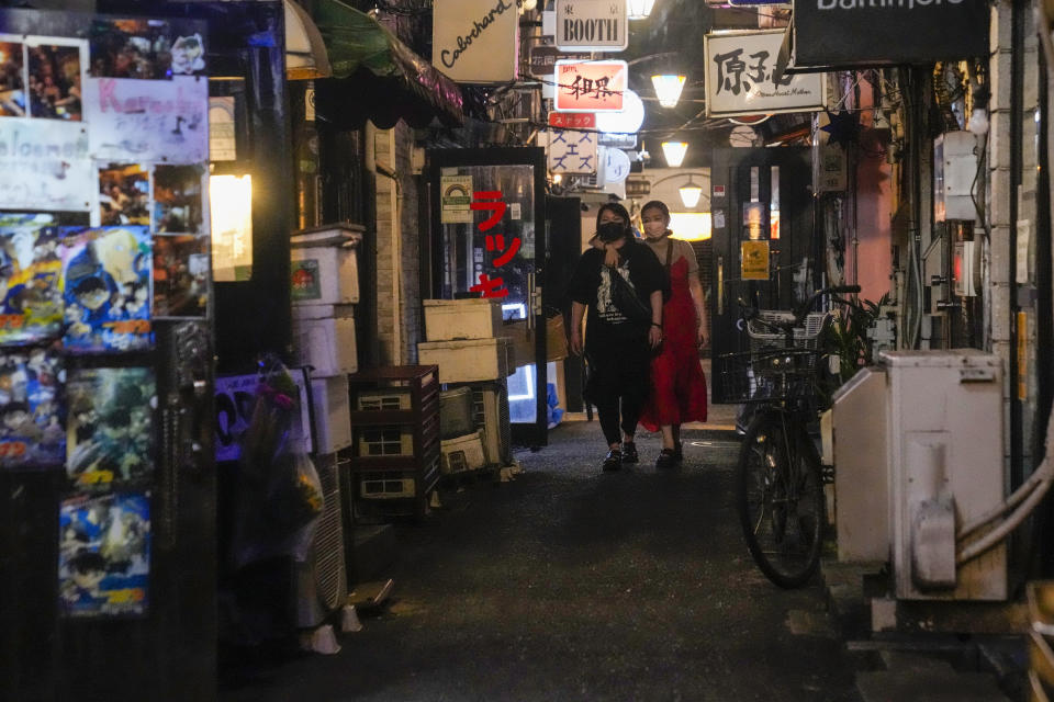 People walk around and gather at a bar after government imposed 8 p.m. closing time for restaurants and bars under Tokyo's fourth state of emergency Saturday, July 17, 2021, in Tokyo. The latest state of emergency has asked restaurants and bars to close by 8 p.m., if not entirely. This has pushed people to drink outside, although many bars remain open and bustling with customers who are defying the rules and expressing frustration and indifference. (AP Photo/Kiichiro Sato)