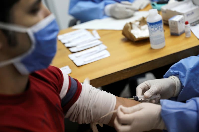 FILE PHOTO: Medical workers take blood samples from a man for a coronavirus disease (COVID-19) rapid test at a medical facility due to the COVID-19 outbreak in Caracas