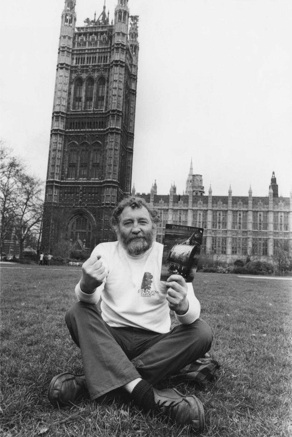 David Bellamy sits in Parliament Square in 1981 with a copy of 'Paradise Lost?', the Friends of the Earth report on the widespread destruction of British wildlife (Getty Images)