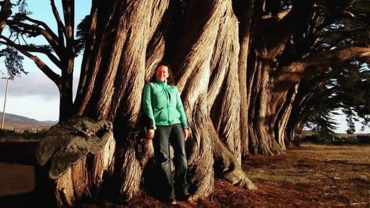 The author leaning against one of the trees along the cypress tunnel in Point Reyes