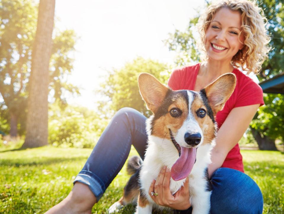 A smiling person takes a dog outside.