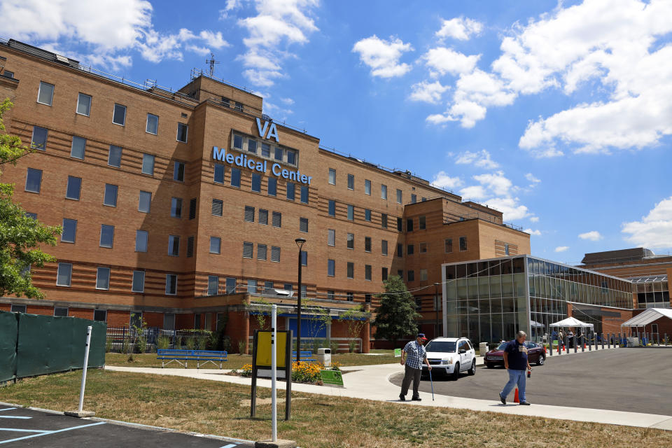 FILE - In this July 14, 2020 file photo, people walk outside the Louis A. Johnson VA Medical Center in Clarksburg, W.Va. A sixth lawsuit has been filed involving the sudden deaths of patients at the West Virginia veterans hospital where a former nursing assistant admitted to intentionally killing seven people with fatal doses of insulin. A federal lawsuit was filed Wednesday, Aug. 19 in the July 2018 death of Russell R. Posey Sr. at the center. (AP Photo/Gene J. Puskar, File)