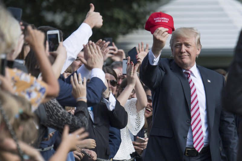 President Donald Trump holds up a "Make America Great Again" hat as he greets visitors at the White House in 2017. A $50 million outreach campaign launched Tuesday by a Republican political action committee aims to reach people in key swing states to showcase GOP voters who won't again vote for Donald Trump, even as he appears likely to grab the 2024 Republican presidential nomination. File Photo by Kevin Dietsch/UPI