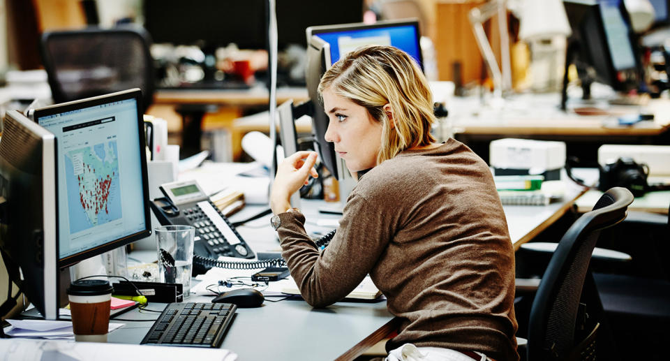 A generic photo of a woman working on her computer in the office.