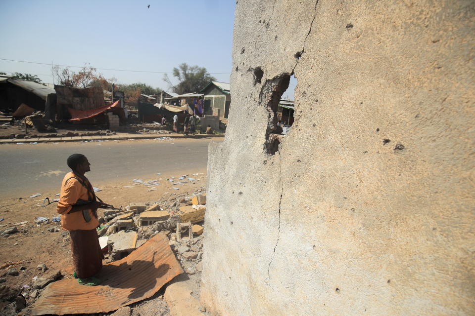 An armed militia stands next to a house damaged during the fight between the Ethiopian National Defence Forces (ENDF) and the Tigray People's Liberation Front (TPLF) forces, in Kasagita town, Afar region, Ethiopia, February 25, 2022. Picture taken February 25, 2022. REUTERS/Tiksa Negeri