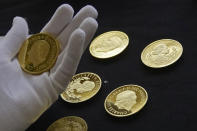 Coins featuring the portraits of King Charles III, right, and Queen Elizabeth II, are assessed during the "Trial of the Pyx,'' a ceremony that dates to the 12th Century in which coins are weighed in order to make certain they are up to standard, at the Goldsmiths' Hall in London, Tuesday, Feb. 7, 2023. A jury sat solemnly in a gilded hall in central London on Tuesday, presided over by a bewigged representative of the crown in flowing black robes, but there were no criminals in the dock. (AP Photo/Kin Cheung)