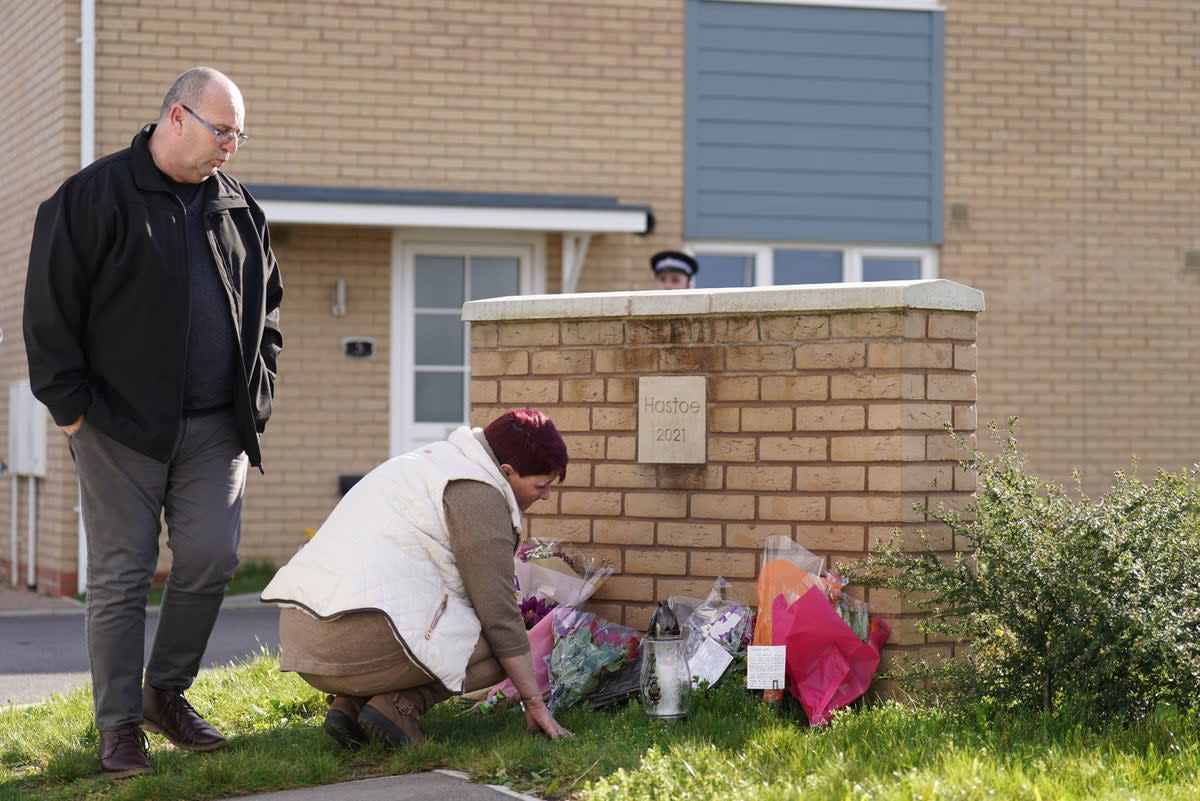 A couple lays flowers at the scene in Meridian Close, Bluntisham, Cambridgeshire, where police found the body of a 32-year-old man with a gunshot wound (PA)