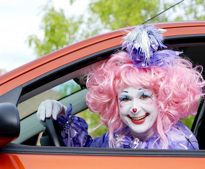 A clown driving a car and smiling