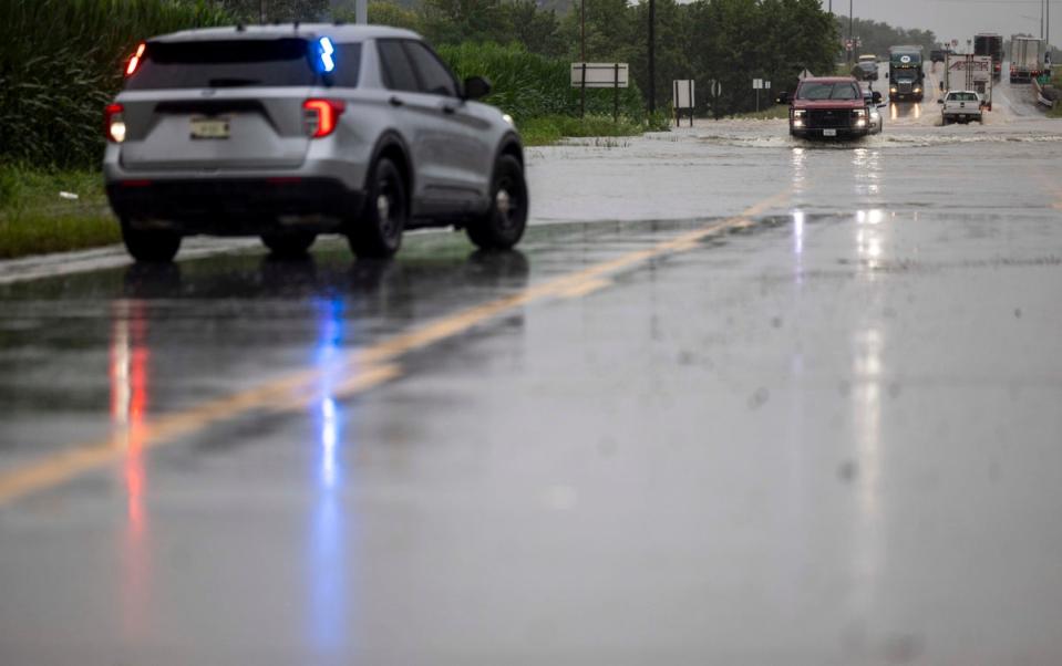 The last set of cars drives through flooding on Illinois State Route 127, south of Interstate 64, before police shut down the road in Nashville, Ill. on Tuesday, July 16, 2024 (AP)