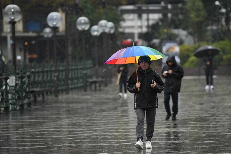 A man shelters from the rain during wet weather at Circular Quay in Sydney.