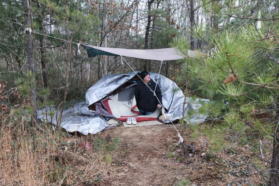 Jeff Sandler looks out from the door of the tent he and his wife Tami have lived in for 10 months in woods in Sanford.