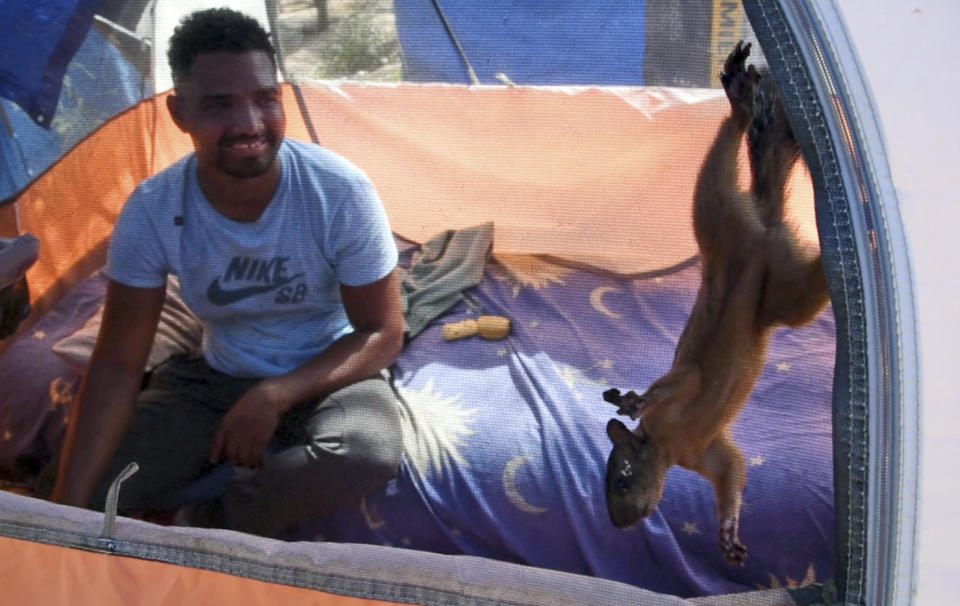 En esta imagen, tomada de un video, Nico, una ardilla, y su dueño, Yeison, en su tienda en un campamento para migrantes, el 20 de septiembre de 2023, en Matamoros, México. Yeison, un migrante venezolano de 23 años, recorrió miles de kilómetros (millas) con su mascota hasta la frontera con Estados Unidos. Pero Yeison y Nico podrían tener que separarse si él consigue entrar a Estados Unidos. (AP Foto/Valerie González)