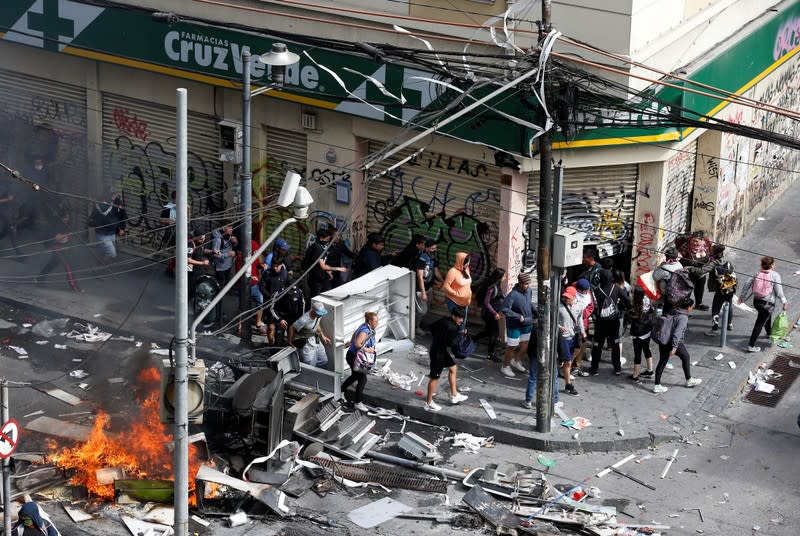 People walk towards a pharmacy during clashes in Valparaiso